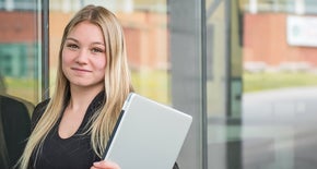 Girl holding her laptop in front of door